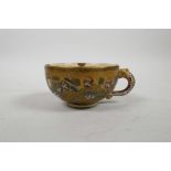 A Japanese Satsuma tea cup decorated with eight auspicious figures and a dragon, indistinctly signed
