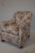 A 1930s scroll arm easy chair, raised on bun feet