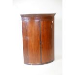 A Georgian mahogany bowfronted hanging corner cupboard with inlaid frieze and boxwood stringing