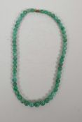 A graduated green jade bead necklace, 17" long