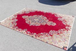 An Iranian silk Kerman carpet with a traditional floral decoration of a red field, circa 1950, 80" x