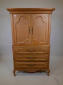 A one piece oak press cupboard, the cupboard fitted with slide for TV, over three long drawers,