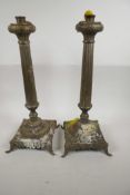 A pair of fluted column candlesticks on square form bases with elephant mask feet, 18" high