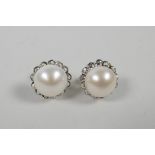 A pair of silver and pearl stud earrings encircled by cubic zirconia