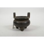 A Chinese bronze two handled censer raised on tripod feet, 4 character mark to base, 4" diameter
