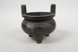 A Chinese bronze two handled censer on tripod feet with script decoration, 4 character mark to base,