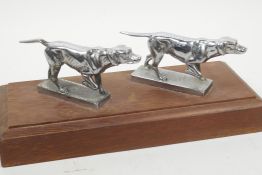 Two silver plated 'setter' dog car mascots mounted on a wooden base, 10½" long
