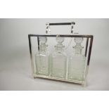 A silver plated three bottle tantalus with three square glass decanters, 11" wide, 12" high