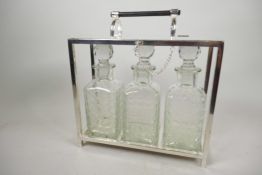 A silver plated three bottle tantalus with three square glass decanters, 11" wide, 12" high