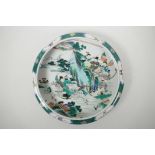 A Chinese famille verte porcelain dish with a rolled rim, decorated with warriors in pursuit of a