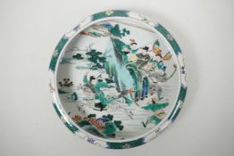 A Chinese famille verte porcelain dish with a rolled rim, decorated with warriors in pursuit of a