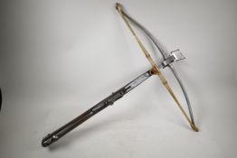 A C19th bullet-shooting crossbow with a cocking lever and release mechanism incorporated into the