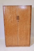 An Art Deco bird's eye maple press cupboard, fitted with shelves, raised on a plinth base, 33" x 23"