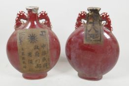 A pair of Chinese porcelain flasks with dragon handles, having all over red glaze, sealed with