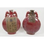 A pair of Chinese porcelain flasks with dragon handles, having all over red glaze, sealed with