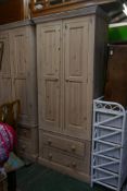 A whitewashed pine two door wardrobe with fielded panels over two long drawers, in two sections, 36"