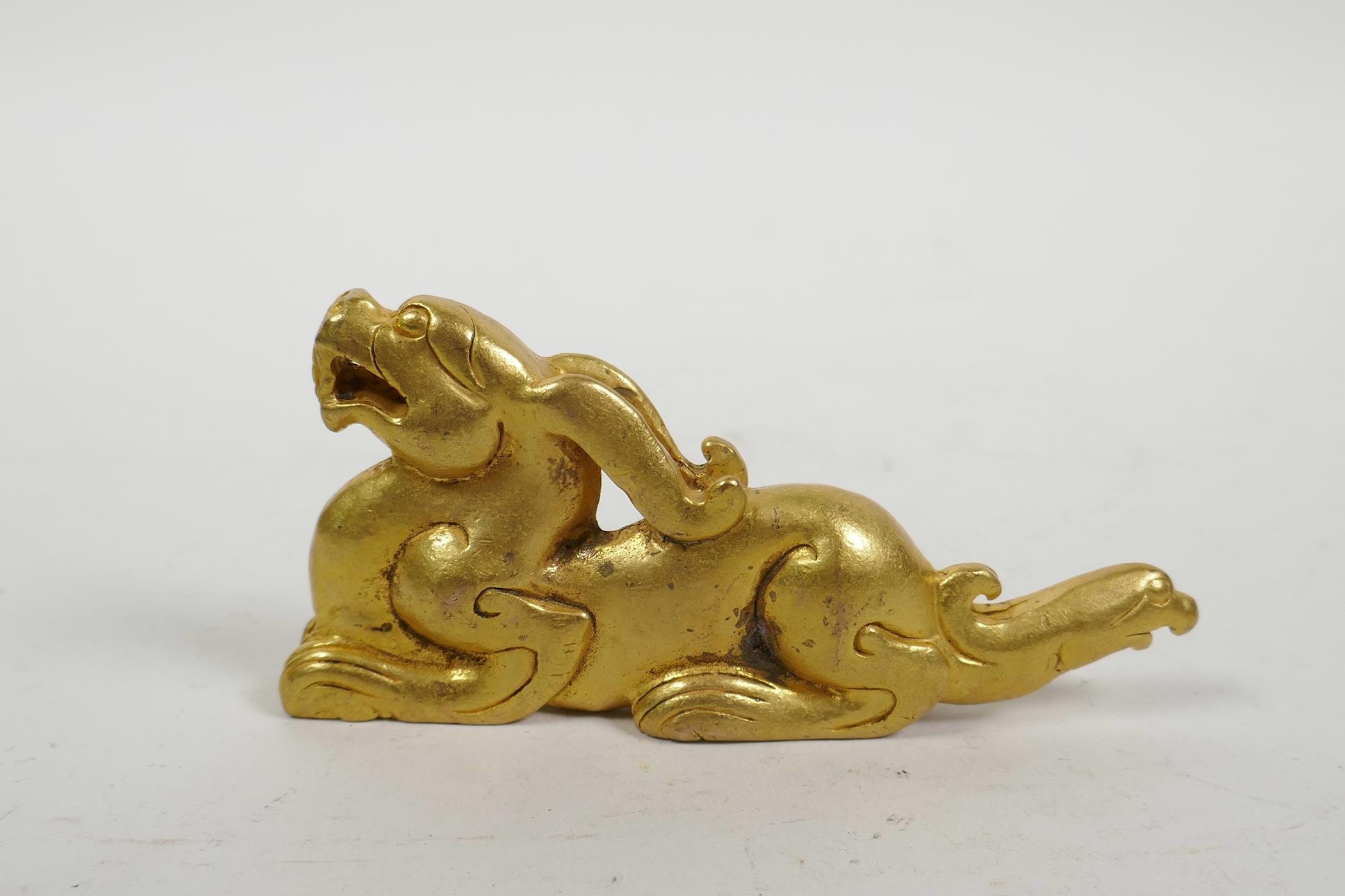 A Chinese gilt metal scroll weight in the form of a kylin, 5" long