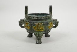 A Chinese bronze two handled censer raised on tripod dragon mask feet, the body decorated with
