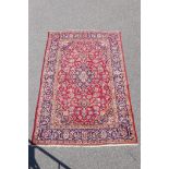 A fine woven old Persian Kashan rug decorated with a multicoloured floral medallion design on a