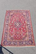 A fine woven old Persian Kashan rug decorated with a multicoloured floral medallion design on a