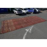 A large C19th Turkmeni red ground carpet with all over geometric design, A/F well worn, 302" x 126"