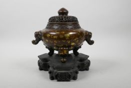 A Chinese bronze censer and pierced cover on tripod supports, with two elephant mask handles and