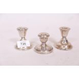 A pair of silver dwarf candlesticks and another similar