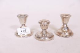 A pair of silver dwarf candlesticks and another similar