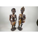 A pair of African carved wood figures of a man and woman, the man smoking a pipe, largest 21½" high