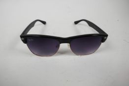 A pair of RayBan sunglasses with black frames and mauve tinted glass in a Lipsy of London hard case