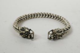 A Chinese white metal ropetwist bangle with dragon decoration to ends, 3" wide