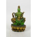 A Tibetan pressed green glass figure of a wrathful deity sitting on a temple lion, 5" high