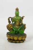 A Tibetan pressed green glass figure of a wrathful deity sitting on a temple lion, 5" high