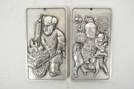 A pair of Chinese white metal scroll weights with raised figural decoration, 2" x 3½"