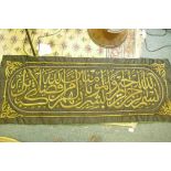 A large Islamic wall hanging having stumpwork decoration of scripture in gold thread, 56" x 23"