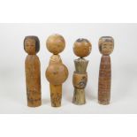 A collection of four Japanese carved and turned wood Kokeshi dolls, signed to the base and sides,