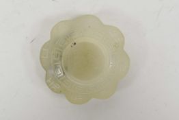 A Chinese carved jade water holder with a scalloped edge and character inscriptions, 2" diameter