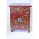 A Chinese red lacquered cabinet with two drawers over two cupboards and painted gilt decoration, 20"