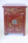 A Chinese red lacquered cabinet with two drawers over two cupboards and painted gilt decoration, 20"