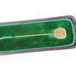 An unmarked gold stickpin set with cabochon coral