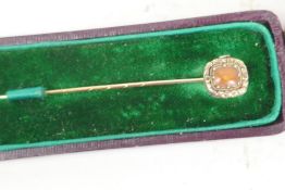 An unmarked gold stickpin set with cabochon coral