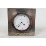 A silver cased bedroom clock by R.J. Carr, the case 4" square with round dial and black hands and