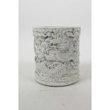 A Chinese moulded porcelain brush pot with raised decoration of dragons above water, impressed