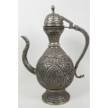 An Islamic white metal teapot with all over embossed floral decoration, 14" high