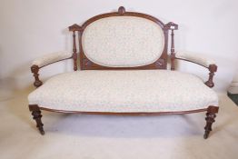 A Victorian walnut open arm settee with carved decoration and bow front, raised on turned, fluted