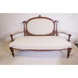 A Victorian walnut open arm settee with carved decoration and bow front, raised on turned, fluted