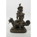 A Sino-Tibetan gilt bronze of a female deity seated on a mythical creature, with distressed gilt