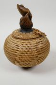 A small Japanese basketwork pot and cover with turned wood pedestal base and carved knop in the form