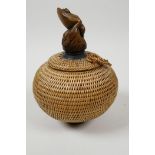 A small Japanese basketwork pot and cover with turned wood pedestal base and carved knop in the form