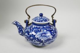 A small Chinese blue and white porcelain teapot with floral decoration and metal handle